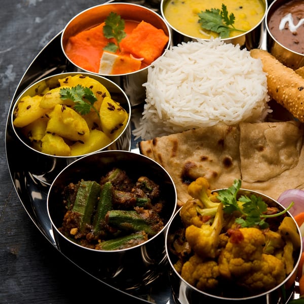 A Mayuri Indian Cuisine thali with various curries, rice, roti, and papadum.