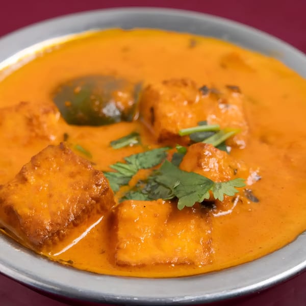 Close-up of Mayuri Indian Cuisine's paneer butter masala, featuring paneer cubes in a rich orange sauce with cilantro.
